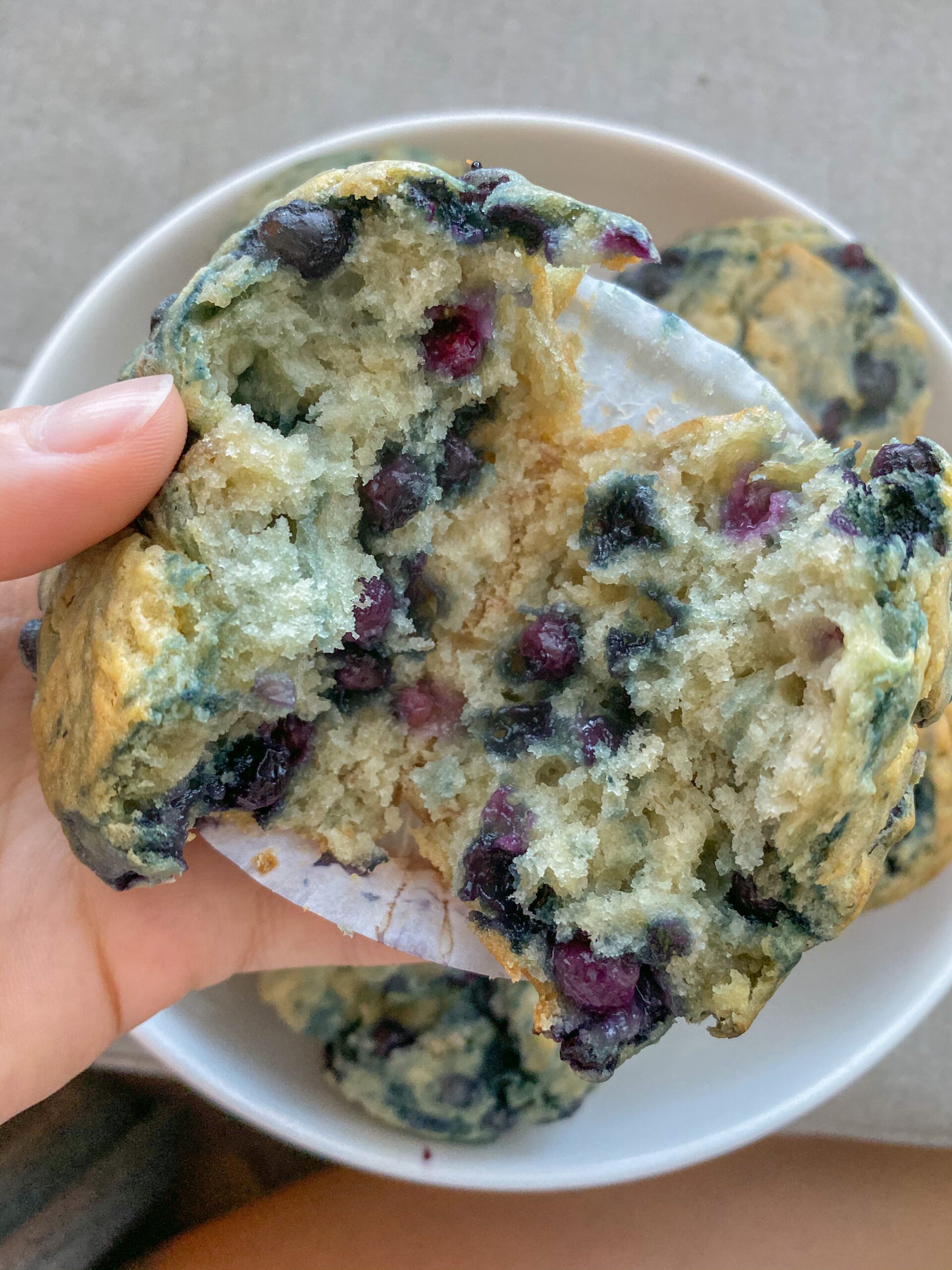 Hand holding blueberry muffin cut in half.