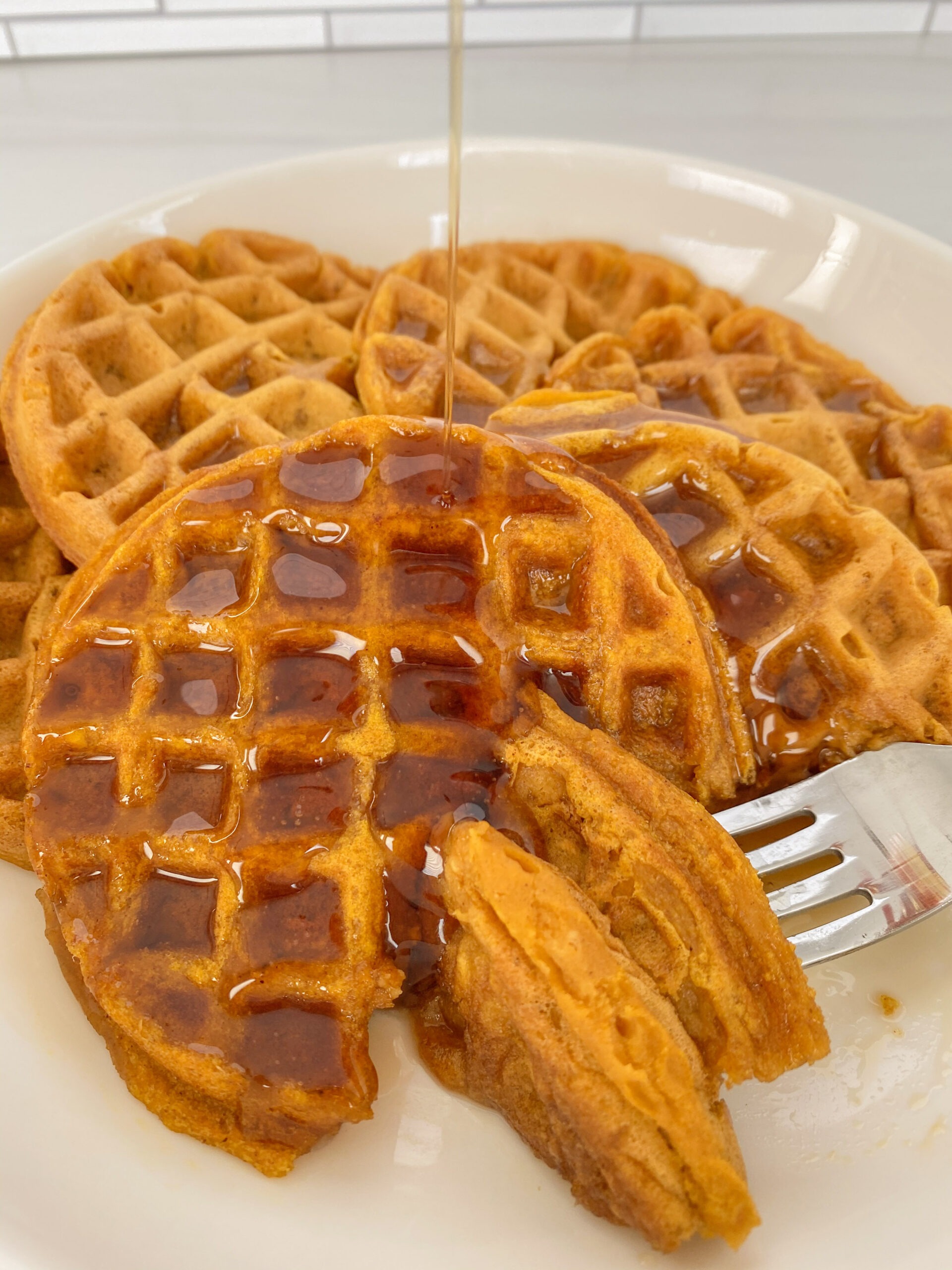 close up of syrup being poured over pumpkin waffles