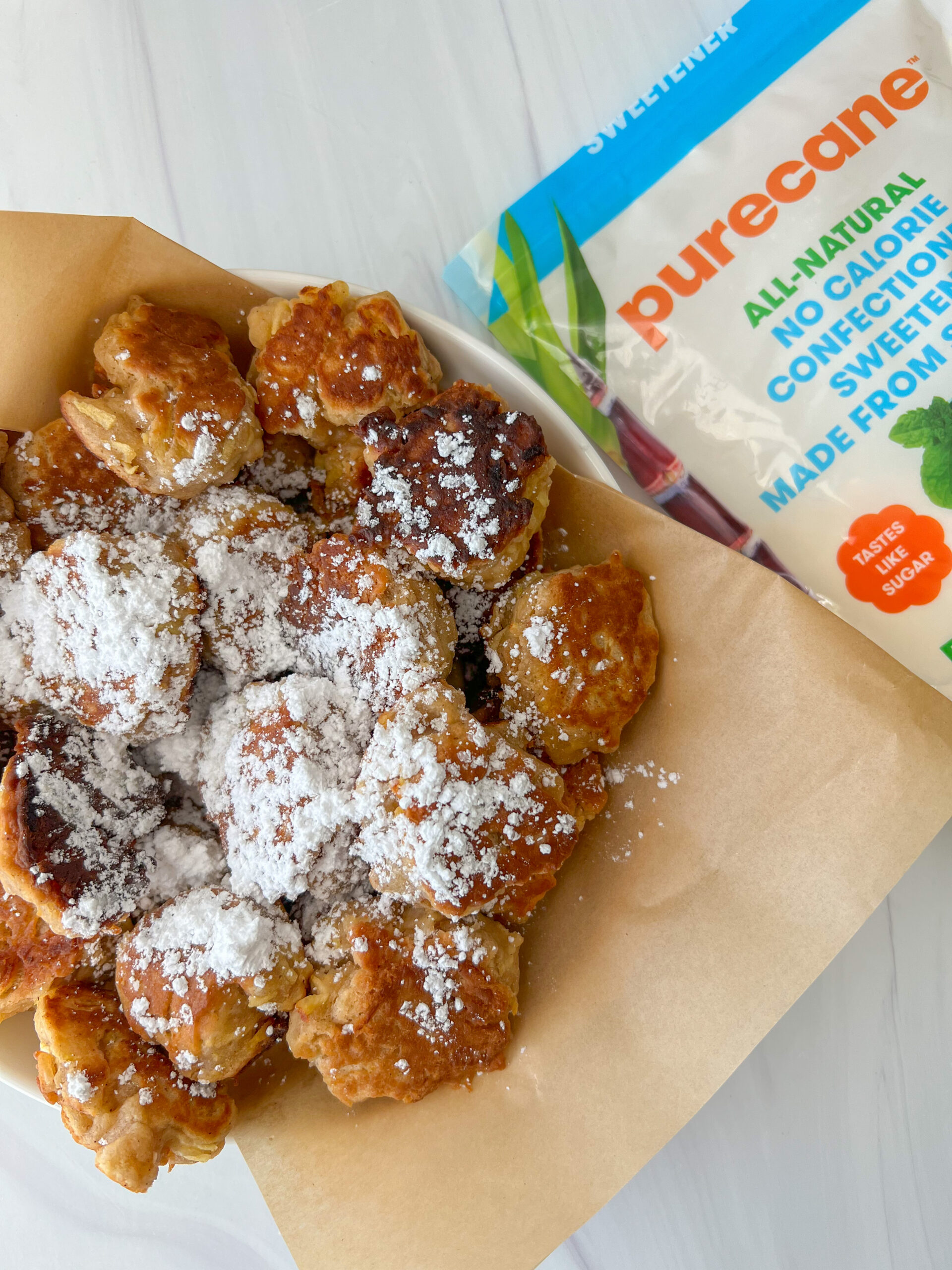 Vegan apple fritters topped with powdered sugar.