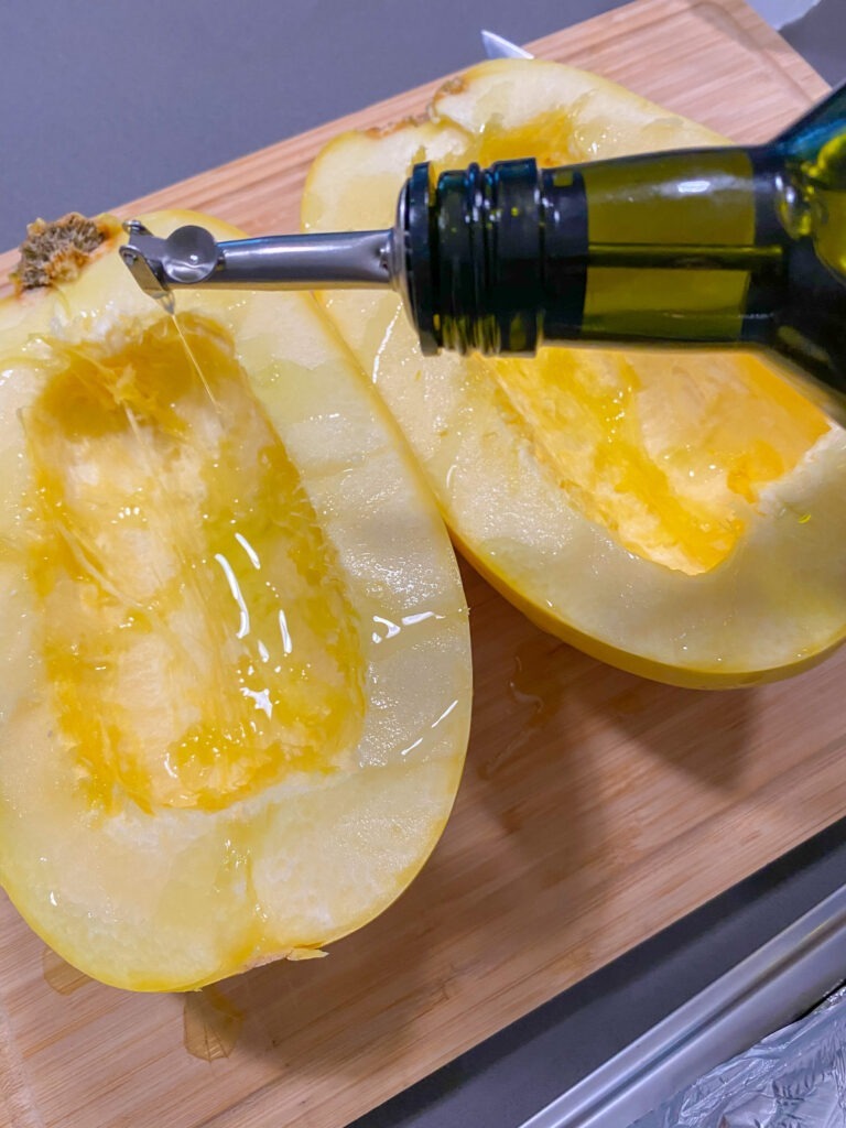 Drizzling a spaghetti squash with olive oil.