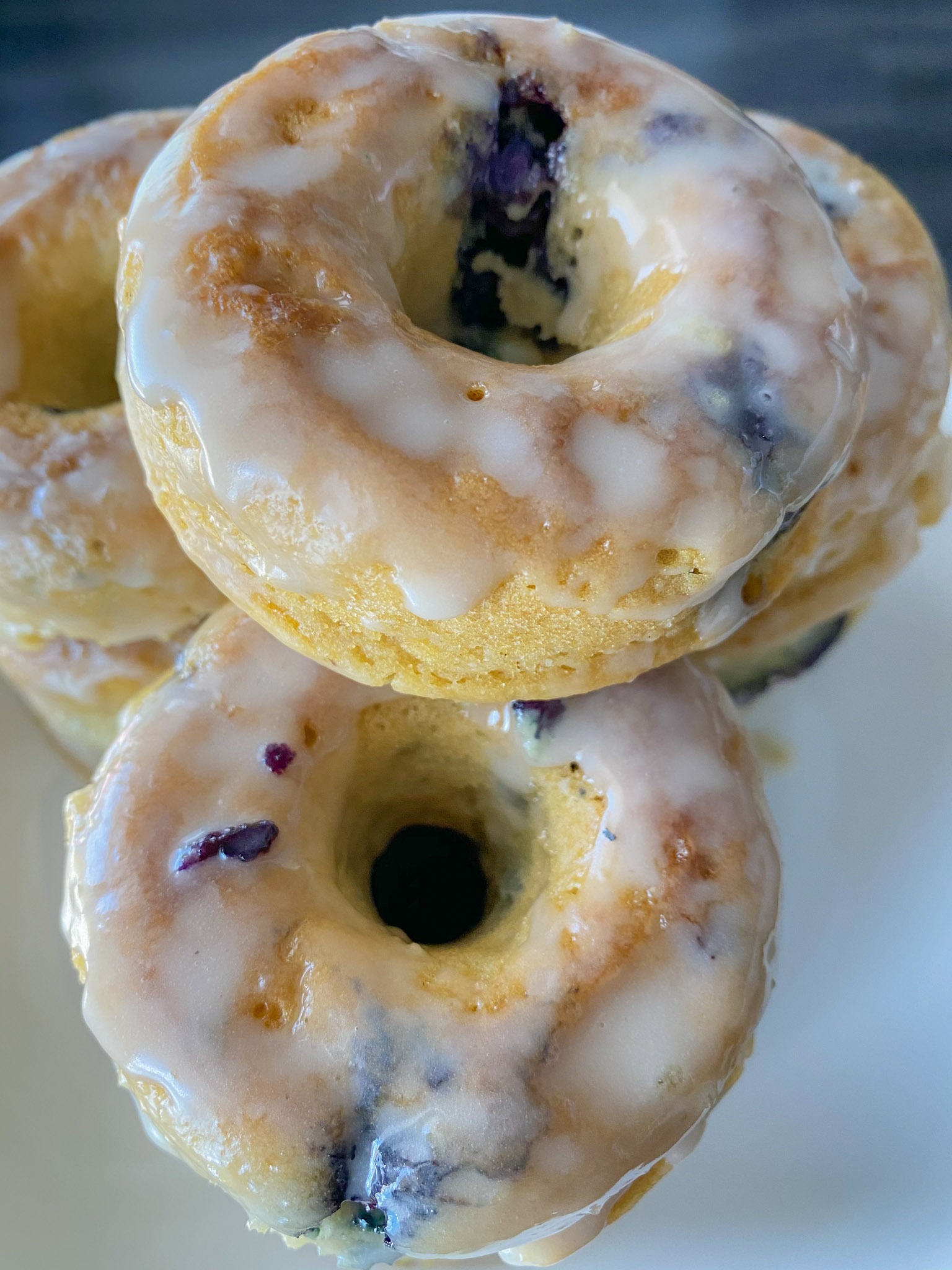 vegan blueberry donuts stacked on top of each other on a white plate. 