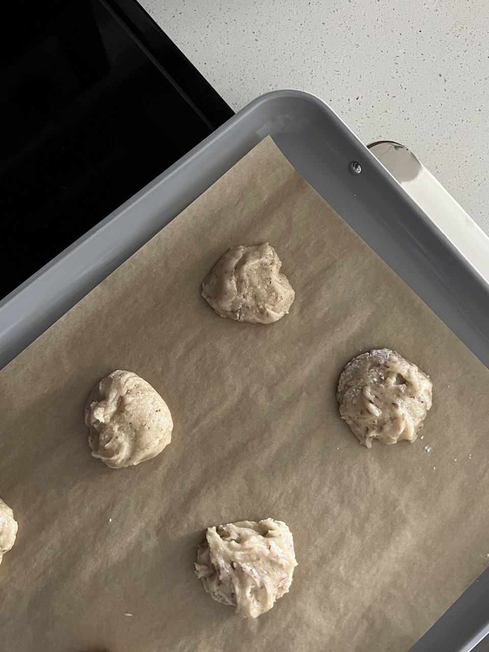 cookie dough in balls on a baking sheet lined with parchment paper. 