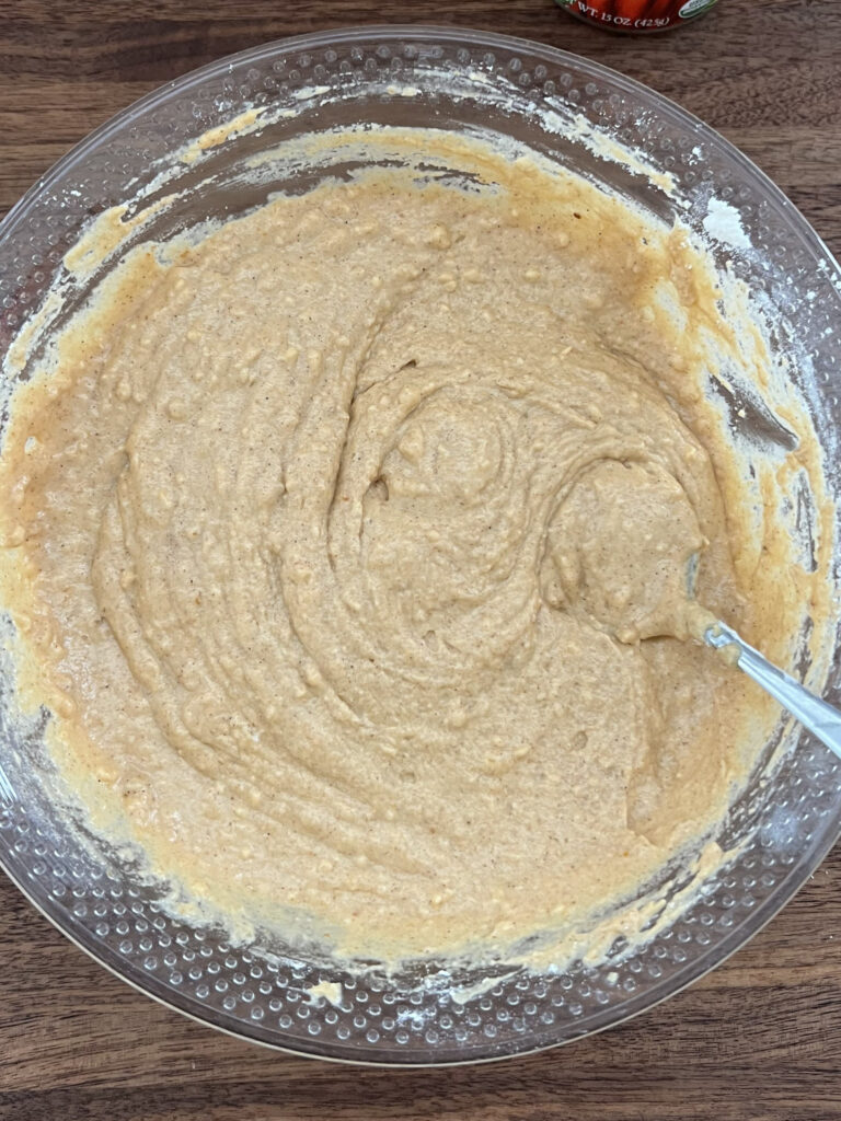 Pumpkin muffin batter mixed in a large mixing bowl.