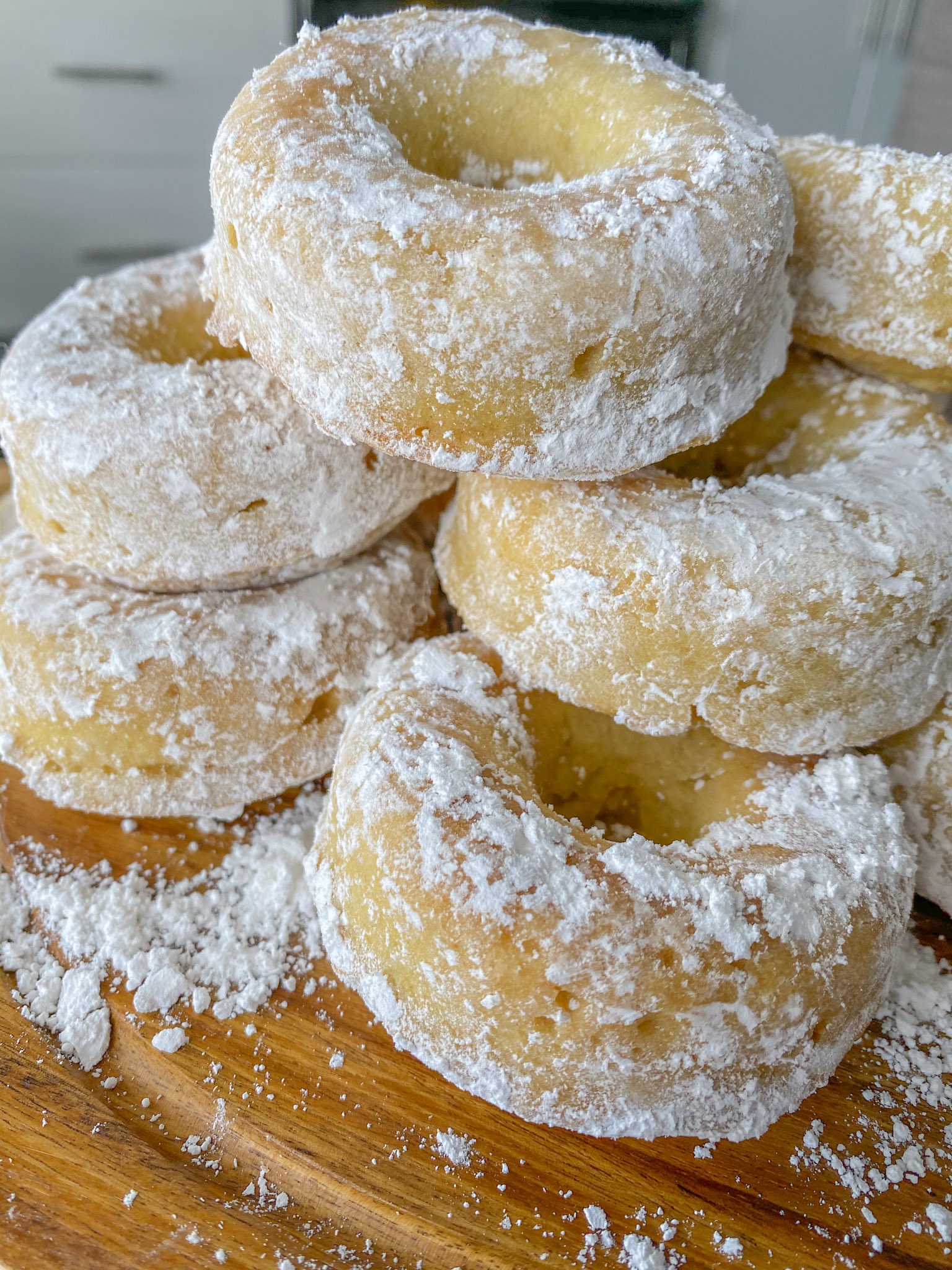 Powdered sugar donuts stacked on a counter.