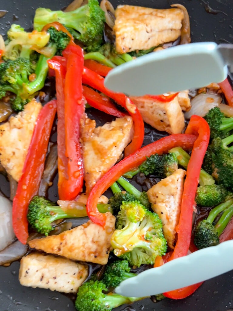 Tofu cooking in a pan with vegetables.