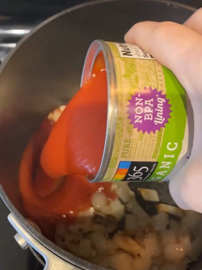 Adding tomato sauce to a skillet.