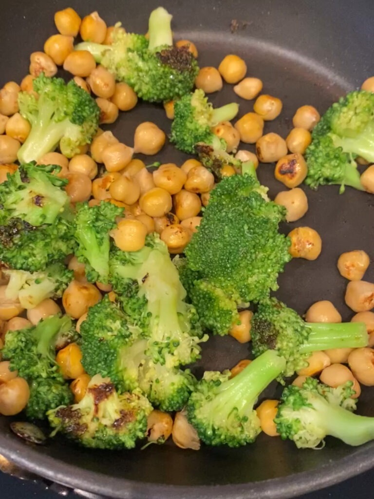 Cooking broccoli and chickpeas in a pan.