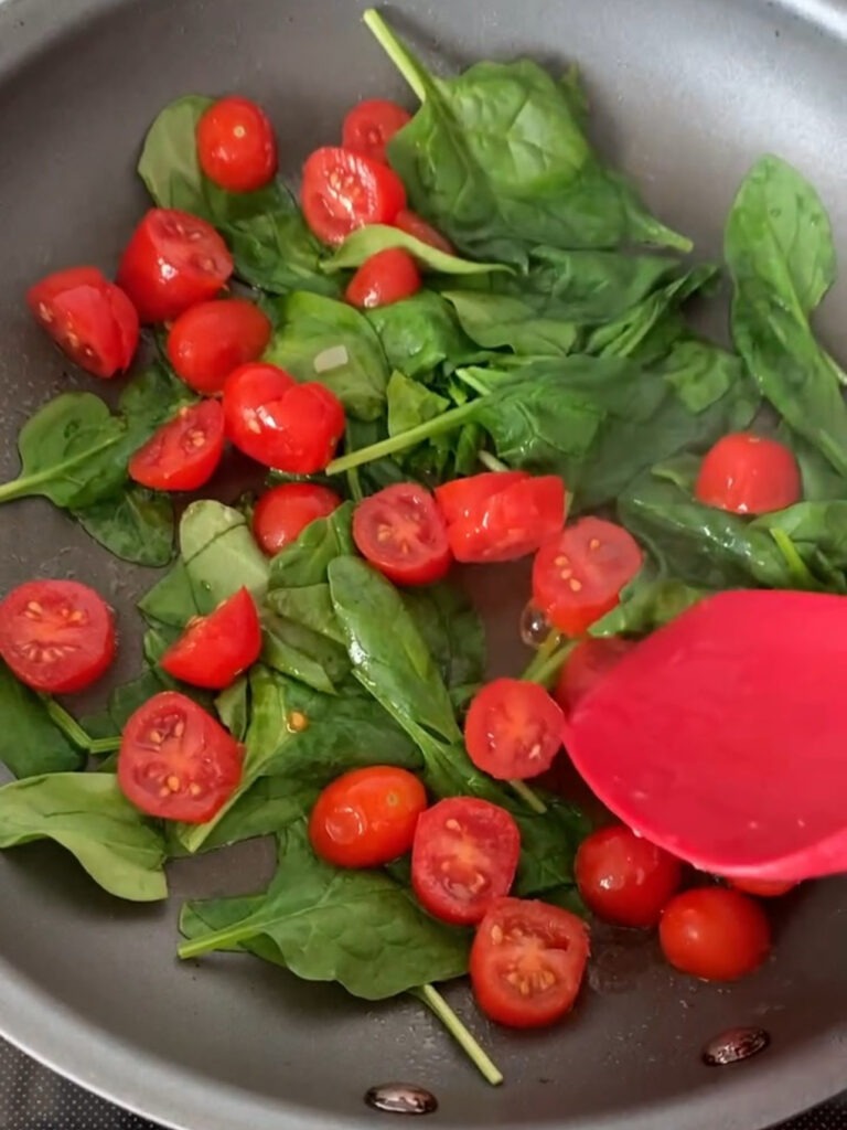 Tomatoes and spinach in a sauté pan. 