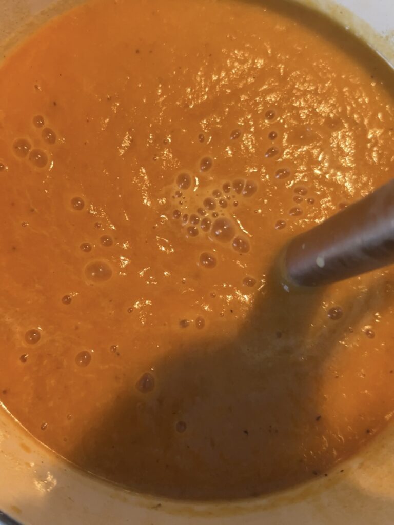 Butternut squash soup being blended with an immersion blender. 