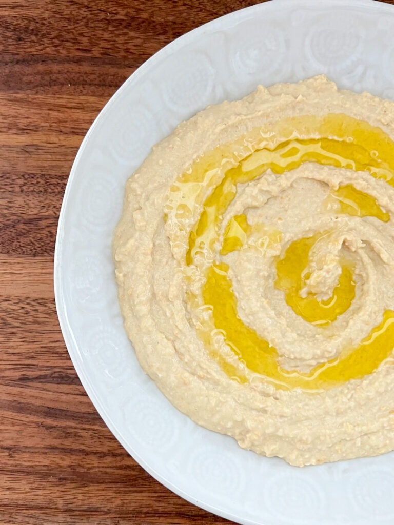 Hummus in a white bowl topped with oil.
