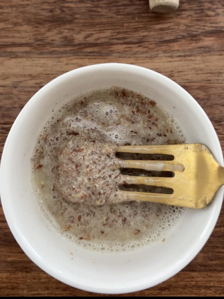 Water and flaxseed meal being mixed with a gold fork. 