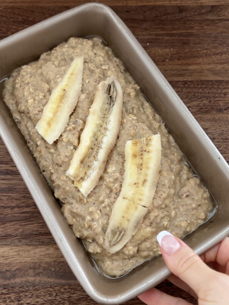 Raw banana on top of the raw batter in a loaf pan. 