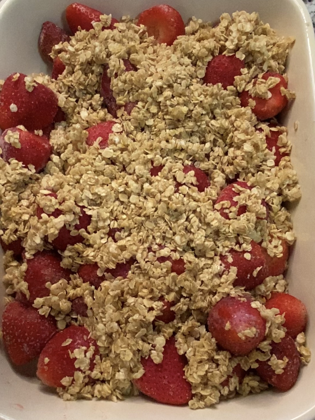 Sprinkling oat topping over strawberries.