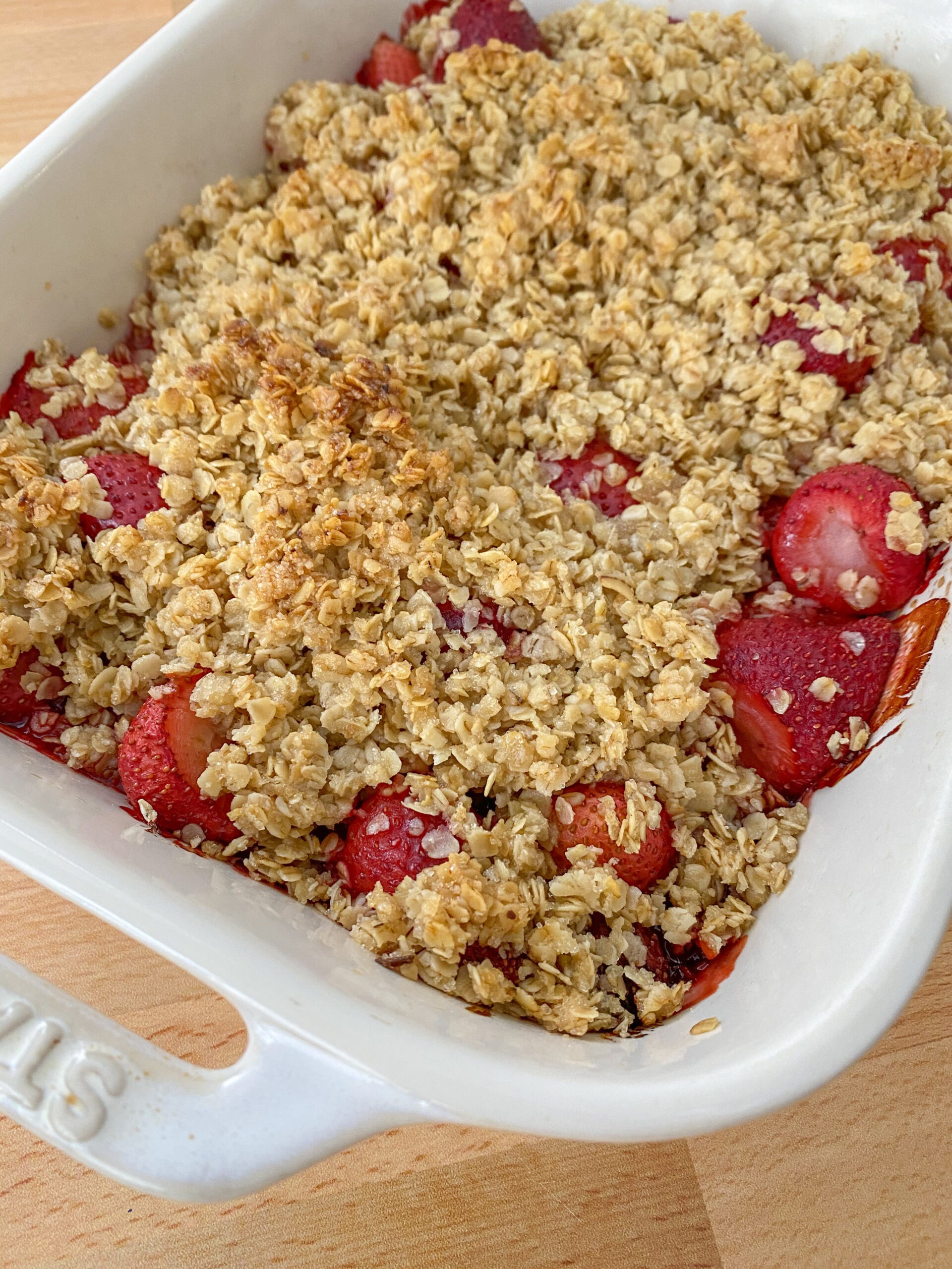 Baked strawberry crumble in a white baking dish.