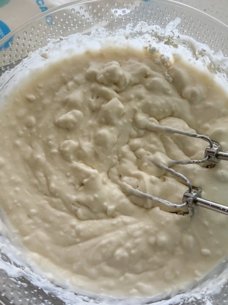 Blending a cream cheese mixture in a large bowl with beaters.