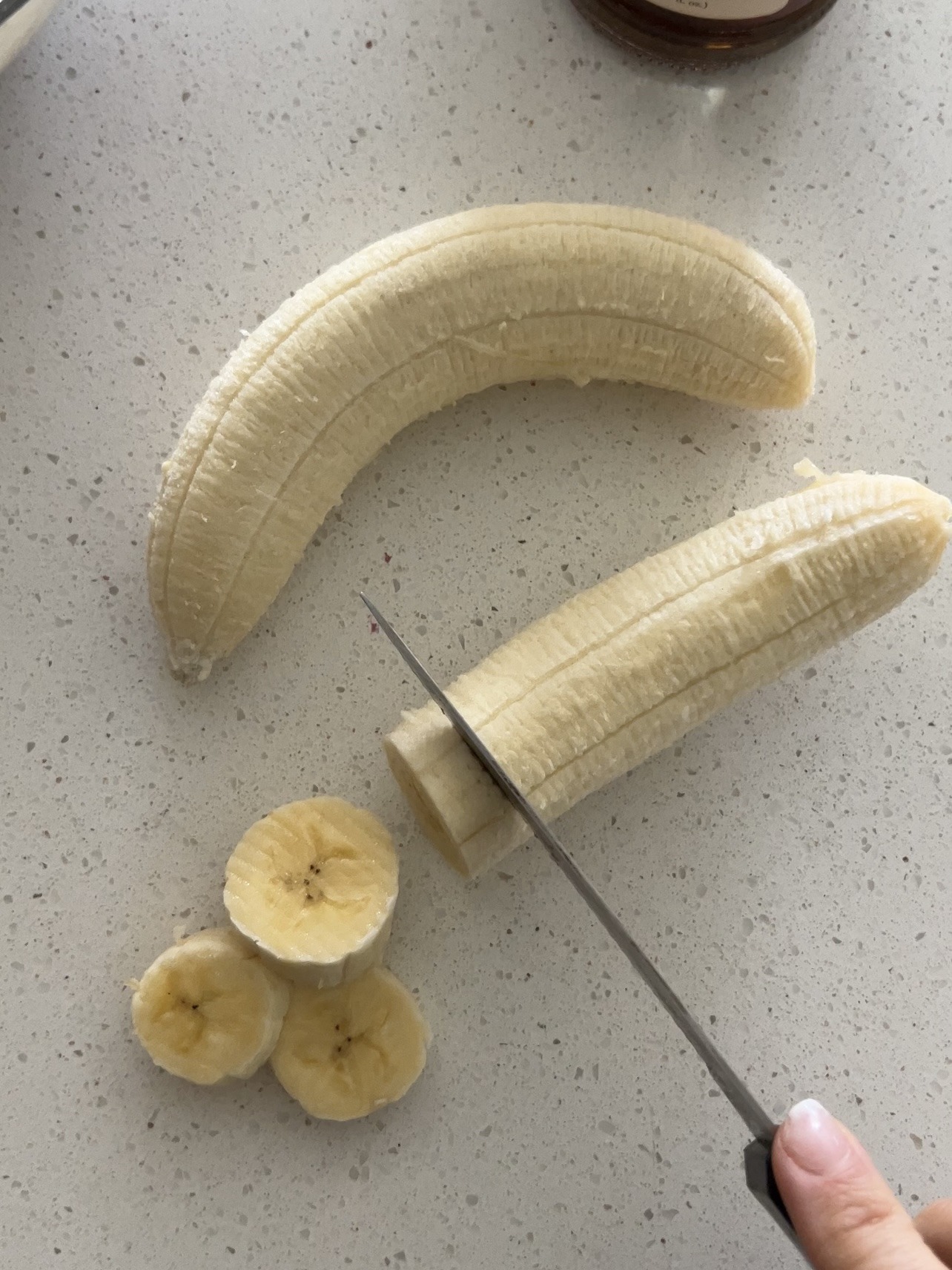 Knife slicing two bananas into medallions. 