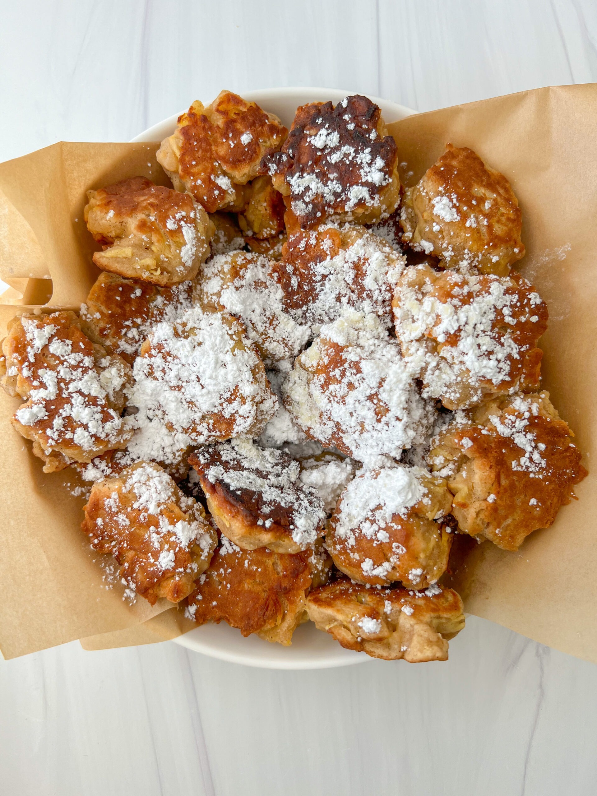 Apple fritters topped with powdered sugar.