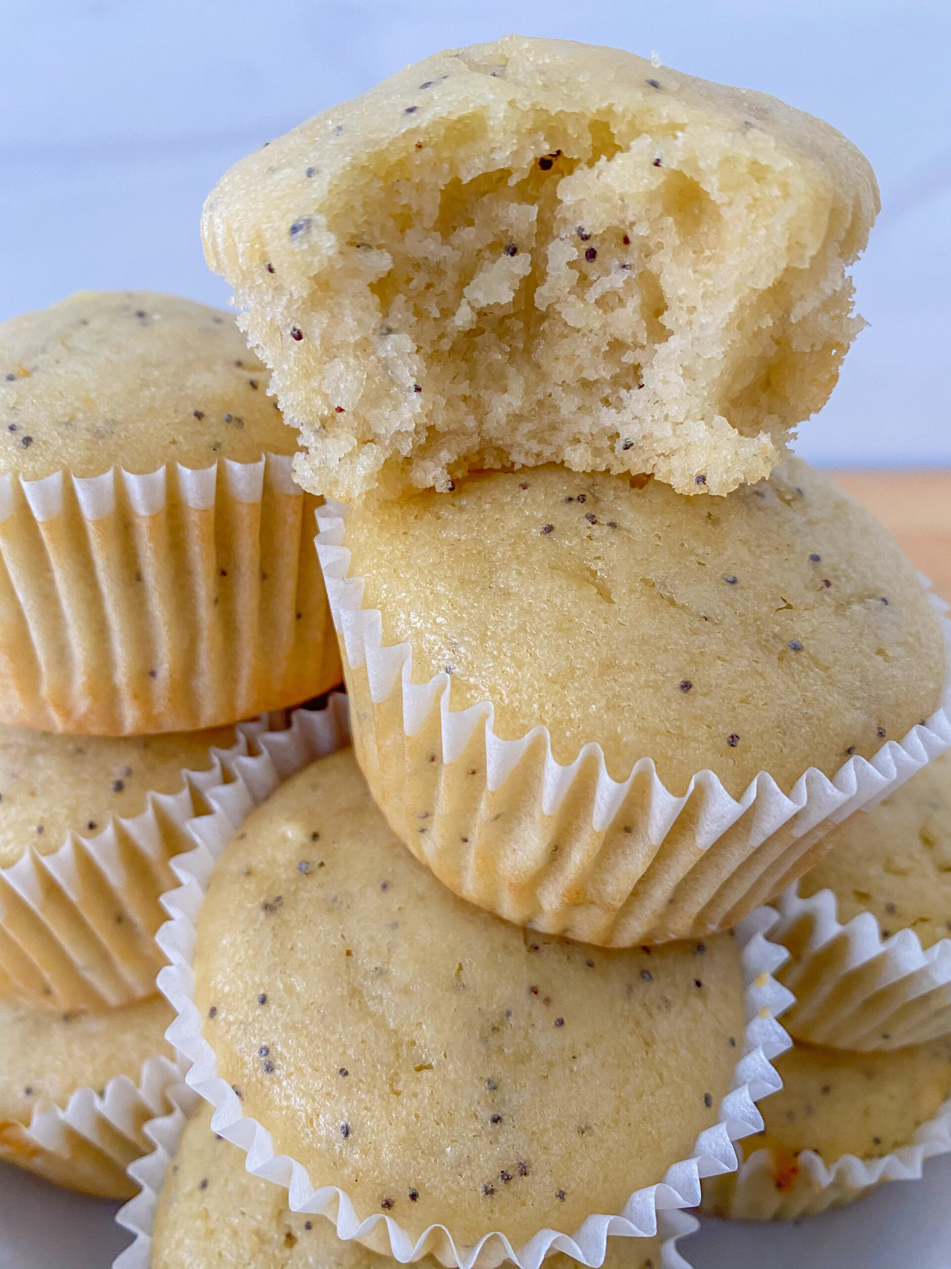 Stack of lemon poppy seed muffins with bite out of one.
