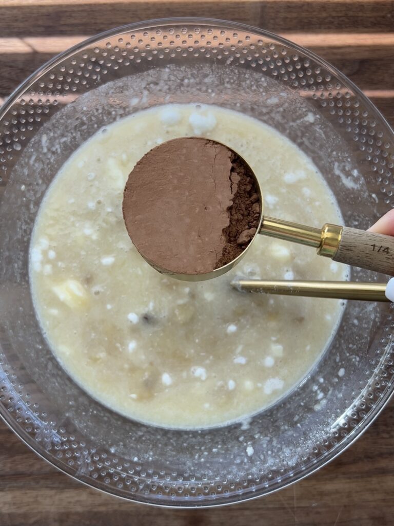 Adding cocoa powder to muffin batter.