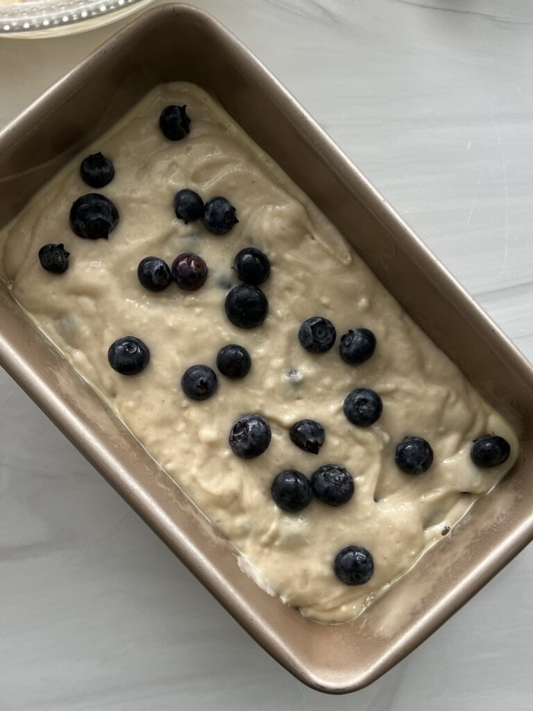 Batter topped with blueberries in a loaf pan.