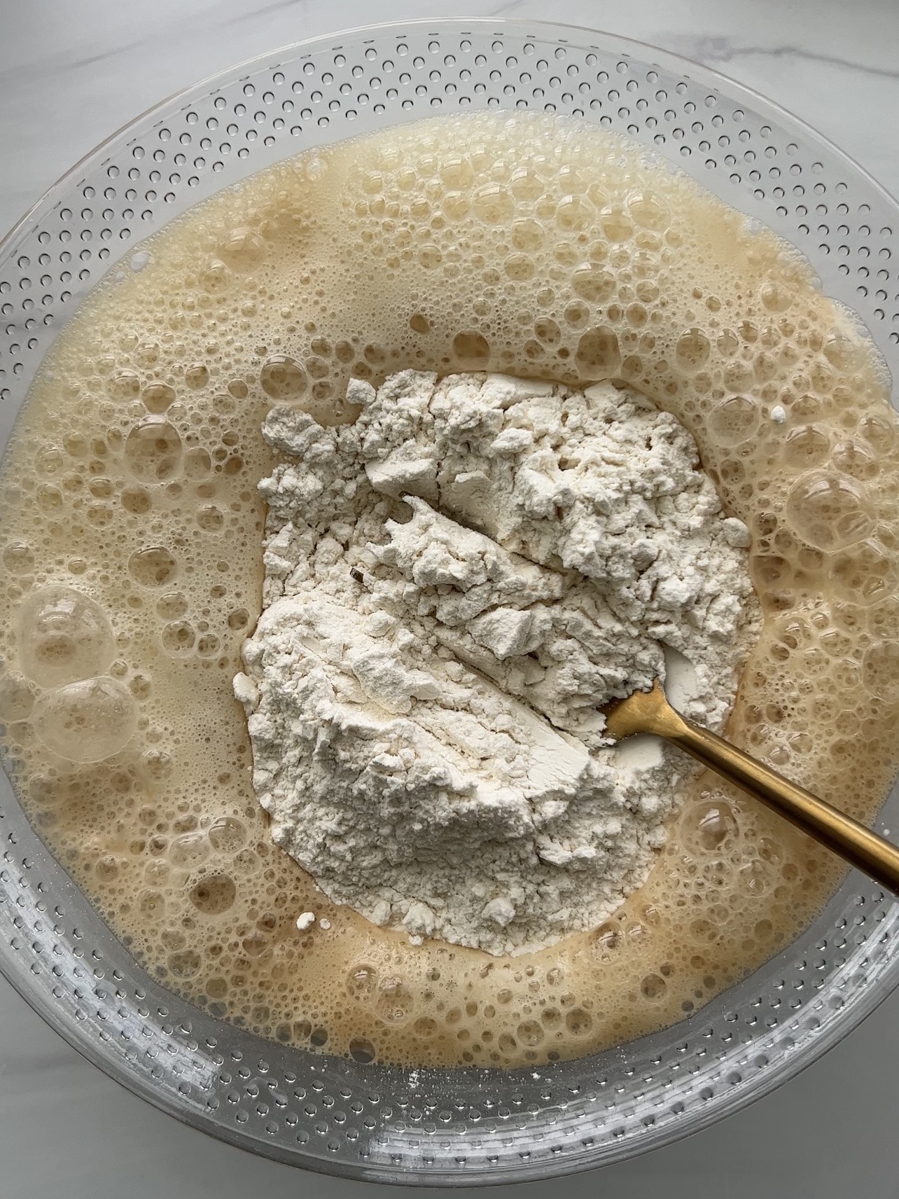Adding flour to dry ingredients in a large bowl.