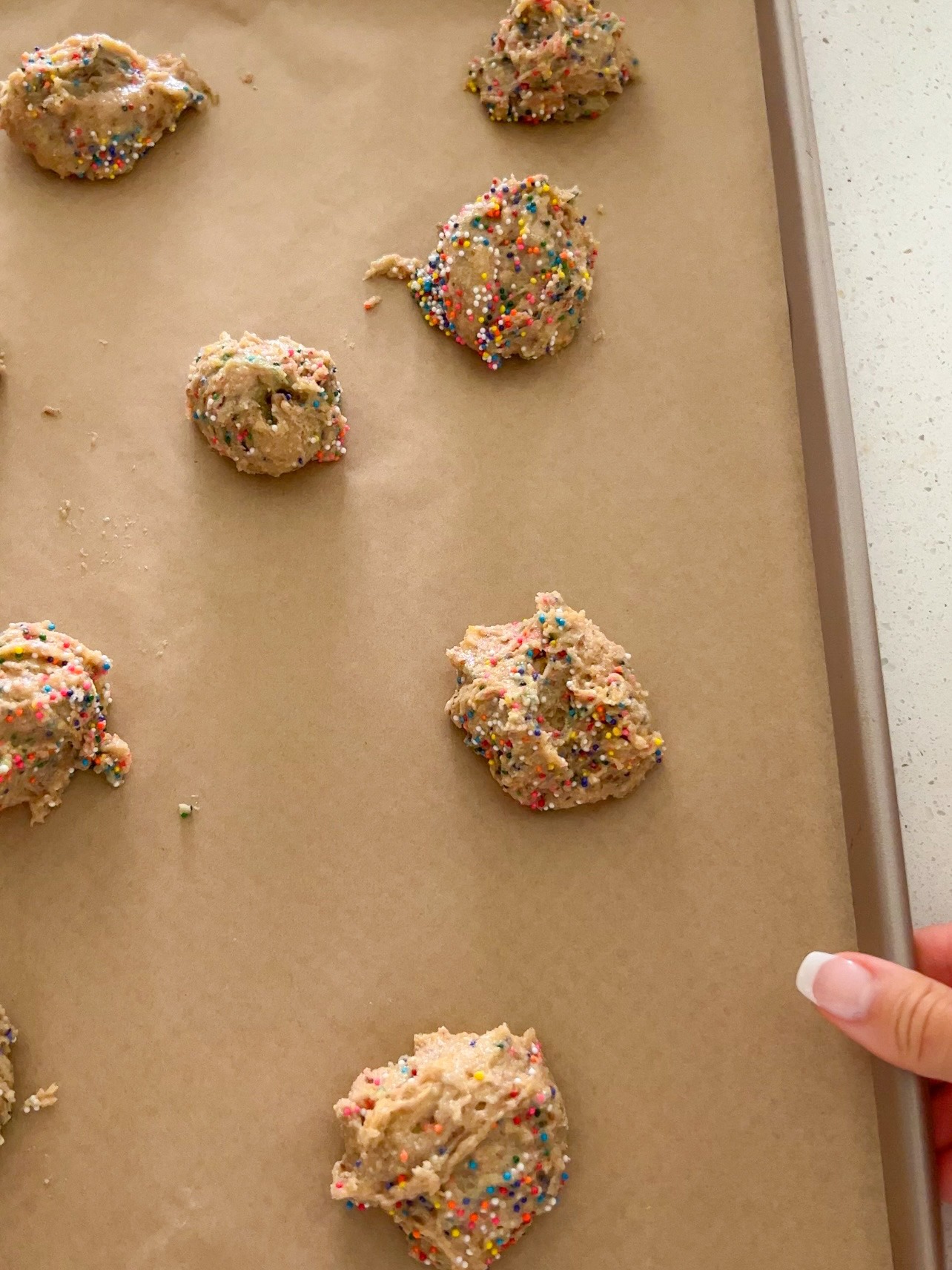 Placing cookie dough on a baking sheet lined with parchment paper.